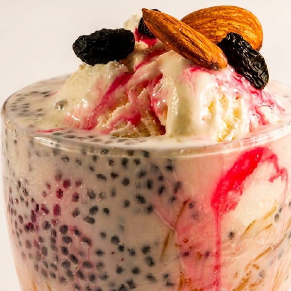 Creamy falooda dessert with ice cream, basil seeds, red syrup, almonds, and raisins.